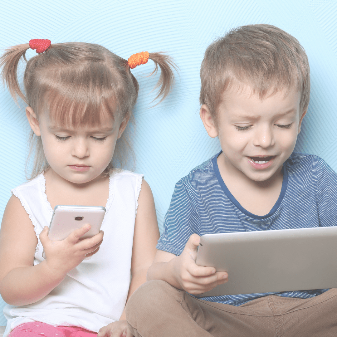 Deux enfants qui regardent un téléphone portable et une tablette.